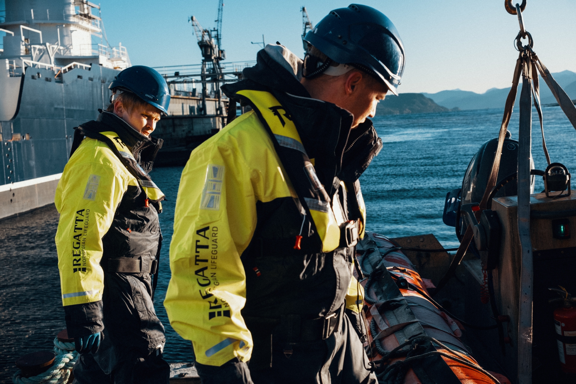 To personer som jobber på sjøen, iført flytedrakt og oppblåsbar redningsvest fra Regatta